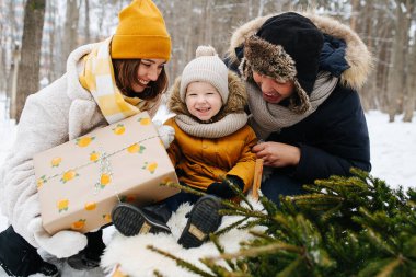 Kış ormanında bir aile, kızakta bir çocuğun yanında bir ebeveyn.