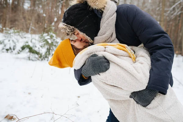 Пара цілується в зимовому лісі, чоловік обіймає дружину — стокове фото