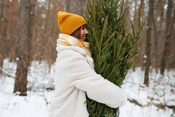 Молода дівчина в зимовому лісі обіймає ялинку — стокове фото