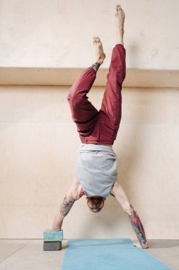 Genç engelli adam duvar desteği ile amuda kalkıyor.