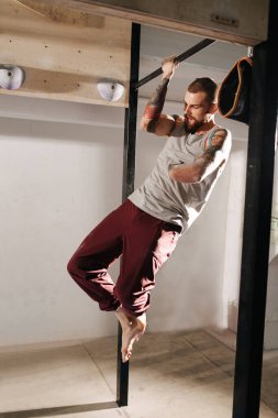 Spor salonunda kolsuz adam çalıştırmak, tek elle barfiks çekmek.