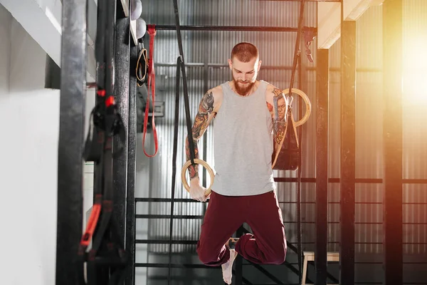 Sterke jonge gehandicapte armloze man training in de sportschool opknoping aan gymnastische ringen — Stockfoto