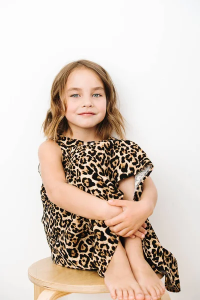 Porträt eines Mädchens, sie sitzt kniend in einem Kleid mit Leopardenmuster — Stockfoto