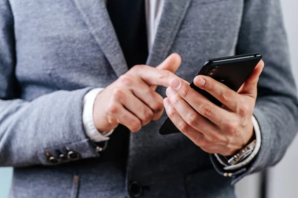Close-up beeld van zakenman handen, hij houdt de telefoon en drukt op het scherm — Stockfoto