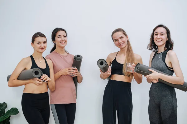 Happy healthy women at yoga club posing for a photo with rolled mats under arms — Stock Photo, Image