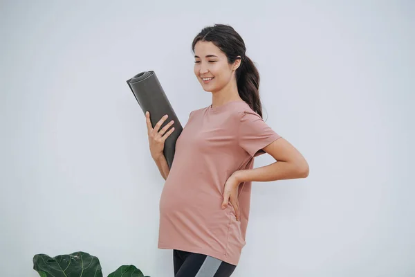 Gelukkig zwangere vrouw in yoga club, met opgerolde mat, poseren voor een foto — Stockfoto