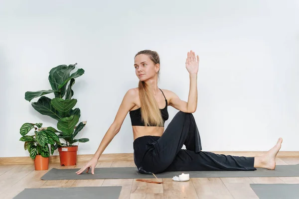 Happy woman practicing yoga doing sitting side twist on a mat in health club — Stock Photo, Image