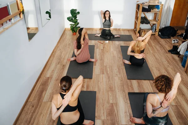 Yoga yapan, parmaklarını arkalarına bağlayan kadınların yüksek açılı görüntüsü.