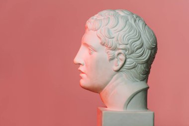 Kırmızı ışıklı pembe arka planda beyaz mermer bir genç adam profili.