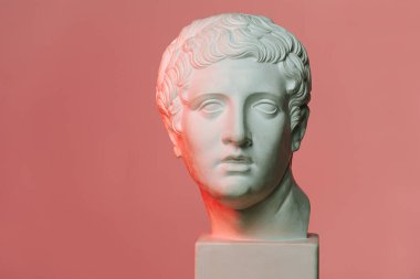 Klasik tarz beyaz mermer. Kırmızı ışıklı pembe arka planda genç bir adamın kafası..