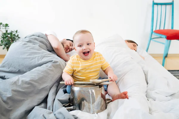 Toddler drums loudly at pots not allowing parents to sleep — Stock Photo, Image