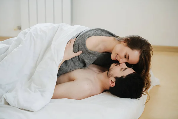 Una giovane coppia sdraiata su un materasso, coperta da una coperta — Foto Stock