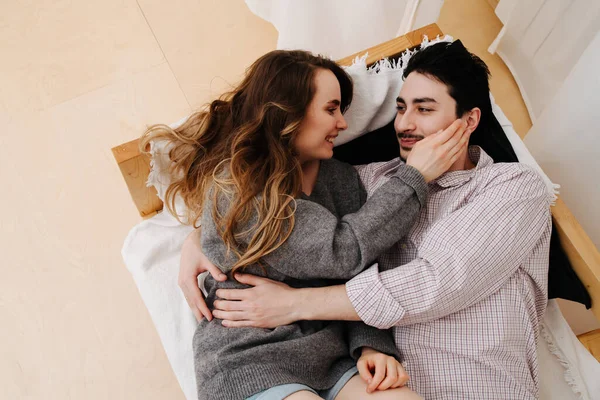 Couple couché sur le lit, la fille touche la tête des gars, et il la serre dans ses bras — Photo