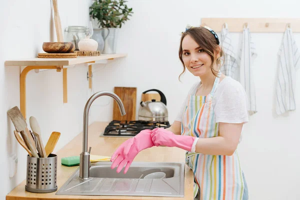 Genç kız eldiven takıyor, bulaşıkları yıkayacak. — Stok fotoğraf