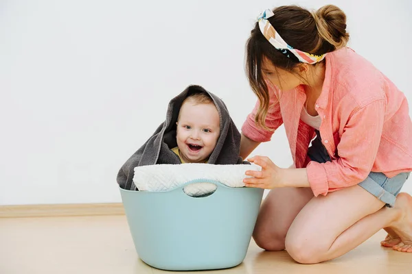 Mom plays with her son, he sits in a basket with clean laundry — Stock Photo, Image