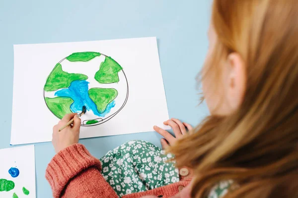 Un concepto medioambiental. Chica pinta un cuadro de tierra verde —  Fotos de Stock
