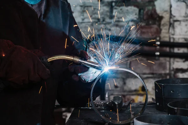 Gas metal arc welding, sparks and blue glow close-up.