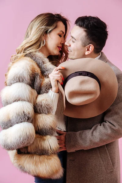 La pareja en el amor abrazos, que están en ropa de invierno con un sombrero en sus manos —  Fotos de Stock