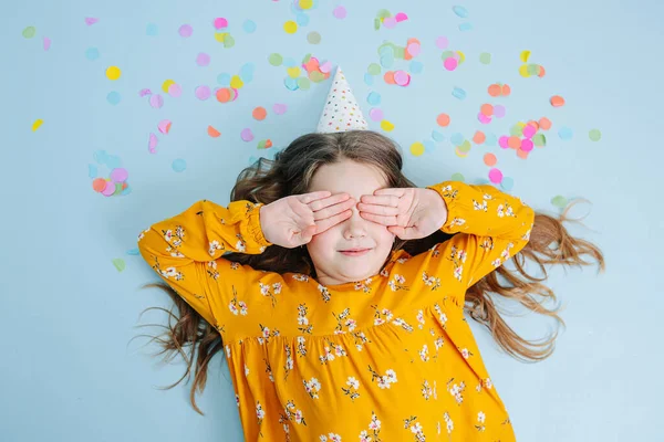 Birthday girl lies on a floor covering eyes with hands — Stock Photo, Image