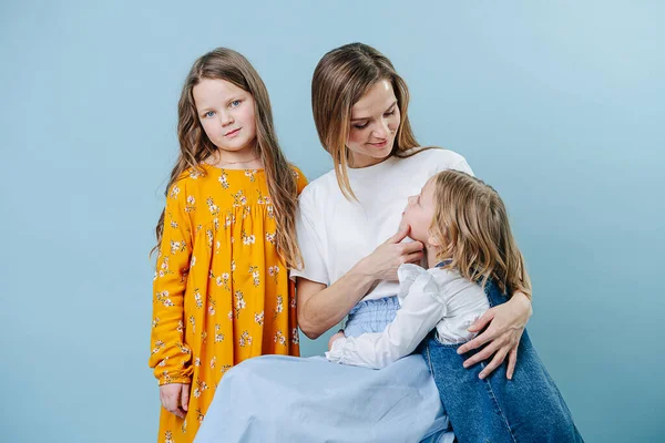 Mamá y dos hijas socializan juntas sobre un fondo azul —  Fotos de Stock