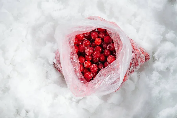 Rolled plastic bag with frozen cherries on a grinded ice. top view.