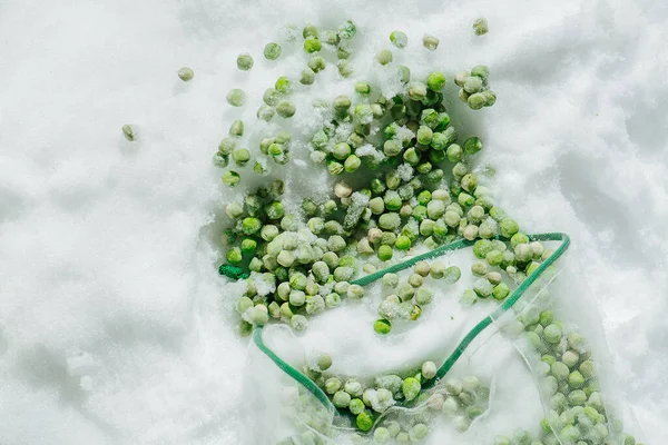 Ervilhas verdes congeladas derramadas caídas do saco líquido. vista superior. — Fotografia de Stock