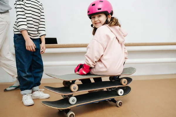 Charmant meisje in roze helm zittend op een triple skate stack op indoor skatepark — Stockfoto