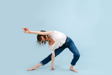 Vücudu yana eğilmiş, yere değen yetenekli çağdaş dansçı..