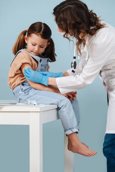 Niña cautelosa que recibe la inyección de la vacuna, mirando la aguja. —  Fotos de Stock