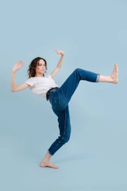 Bacağını kaldıran, geriye doğru eğilen, adım atan modern dansçı.