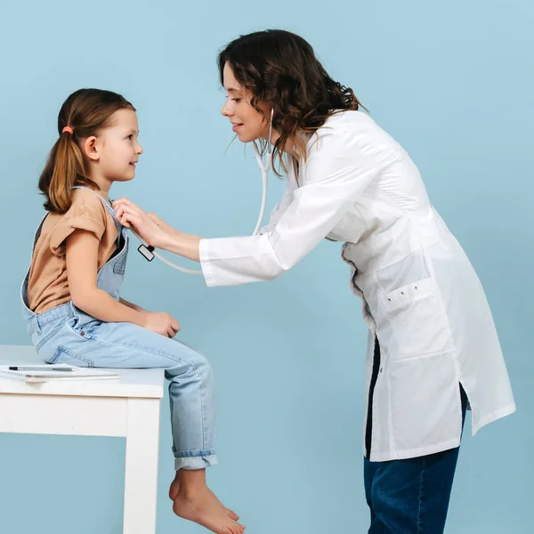 Amistosa Doctora Joven Examinando Una Niña Con Estetoscopio Vista Lateral —  Fotos de Stock