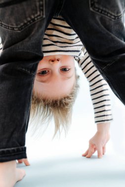 Aptal sarışın çocuk öne eğiliyor, bacaklarının arasına bakıyor. Mavi üzerine