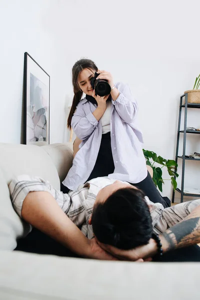 Casal íntimo, homem deitado em um sofá, mulher sentada nele, tirando foto — Fotografia de Stock