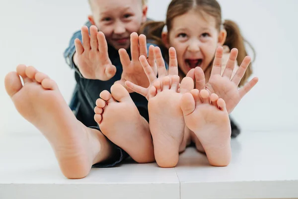 Dont tickle. Little siblings sitting on a table with bare feet. Stop gesture — Stock Photo, Image