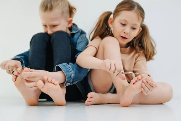 Ragazzi divertenti. Piccoli fratelli con i piedi nudi tagliando unghie sulle dita dei piedi. — Foto Stock