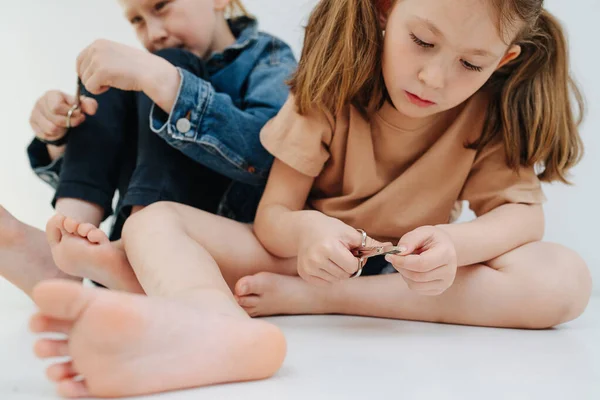 Веселі діти. Маленькі брати і сестри з голими ногами відсікають нігті . — стокове фото