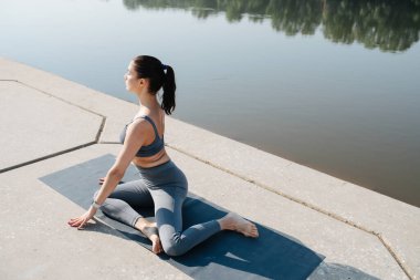 Huzurlu esmer, nehir kenarındaki güzel bir yerde yoga yapıyor.