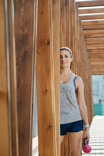 Portret van een gelukkige brunette poseren buiten onder een houten frame tunnel — Stockfoto