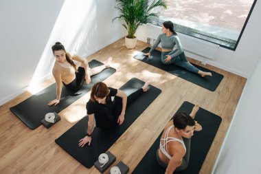 Yoga yapan, yan tarafa kıvrılan bir grup insanın yüksek açılı görüntüsü.