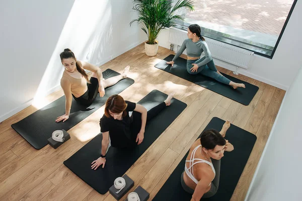 Yoga yapan, yan tarafa kıvrılan bir grup insanın yüksek açılı görüntüsü.