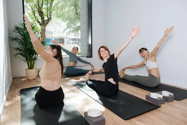 Eğitmen önünde yoga yapan, yan eğilme yapan mutlu gülümseme grubu.