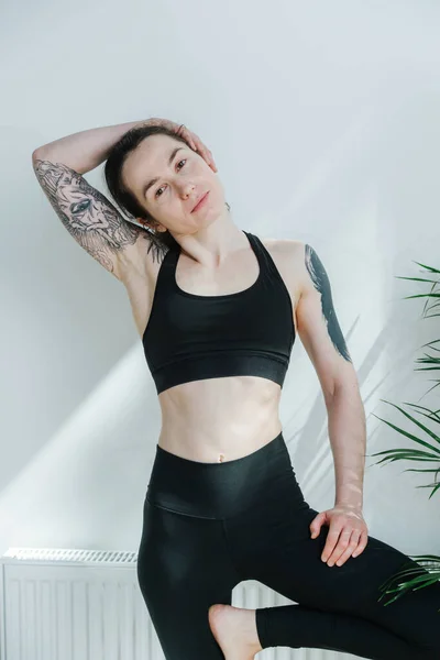 Portret van een jonge vrouw met schoudertatoeages poserend in een yoga sportkleding — Stockfoto