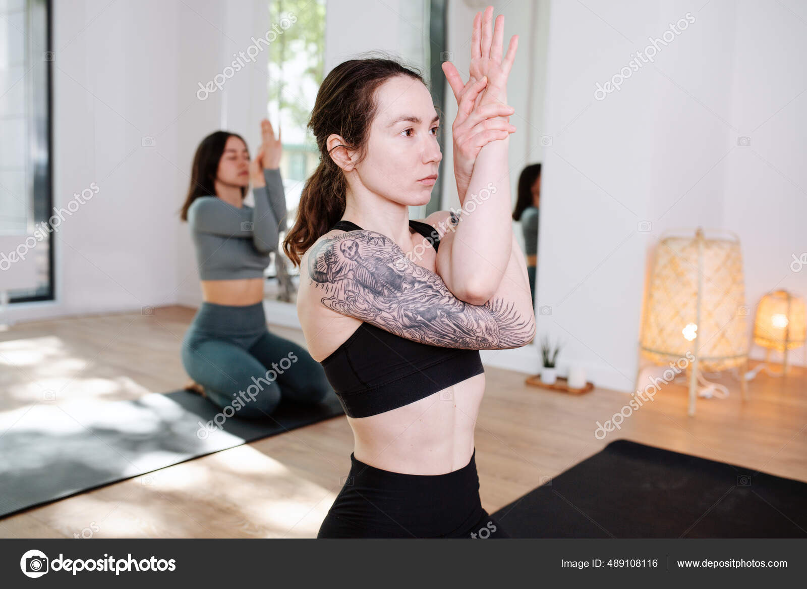 Conentrated women practicing yoga in a group, meditating with arms  interlaced Stock Photo by ©zzzdim 489108116