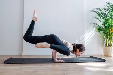 Omuz dövmesi olan yetenekli bir kadın büyük bir stüdyoda yoga amuda kalkmayı savunuyordu. Yan görünüm