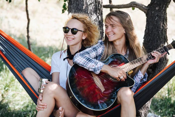 Amigos Sentados Juntos Una Hamaca Disfrutando Música Guitarra Sonriendo Una — Foto de Stock