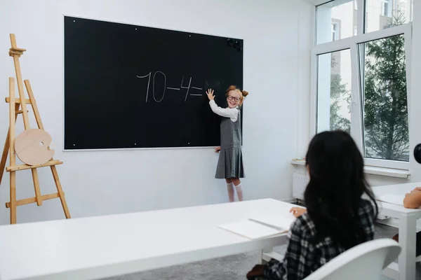 在课堂上一个黑板上 一个非常友好的女学生正在解一个基本的数学题 看着她的蜡像 前景一片光明 — 图库照片