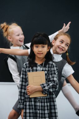 Fotoğraf için poz veren, dans eden üç şutçu kız. Sınıfta bir balkonun önünde diğerinin arkasında durmak..