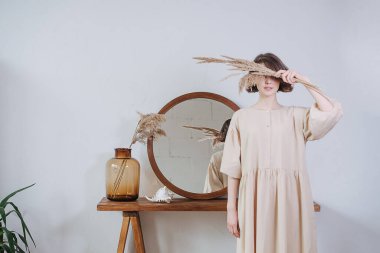 Yazlık elbiseli, yüzünde mısır gevreği kulakları olan genç bir kadının yaratıcı portresi. Kapalı mekanda kısa saçlı güzel bir esmer. Arka planda ayna var. Düşük ihtimal.