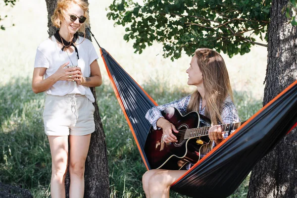 Dos mujeres mirándose. Uno está sentado en una hamaca, tocando la guitarra — Foto de Stock