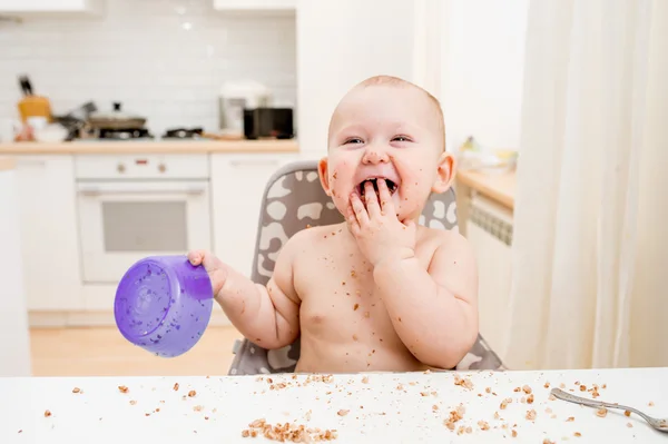 Lilla bebis äter på kök. Happy rörigt Enger Stockfoto